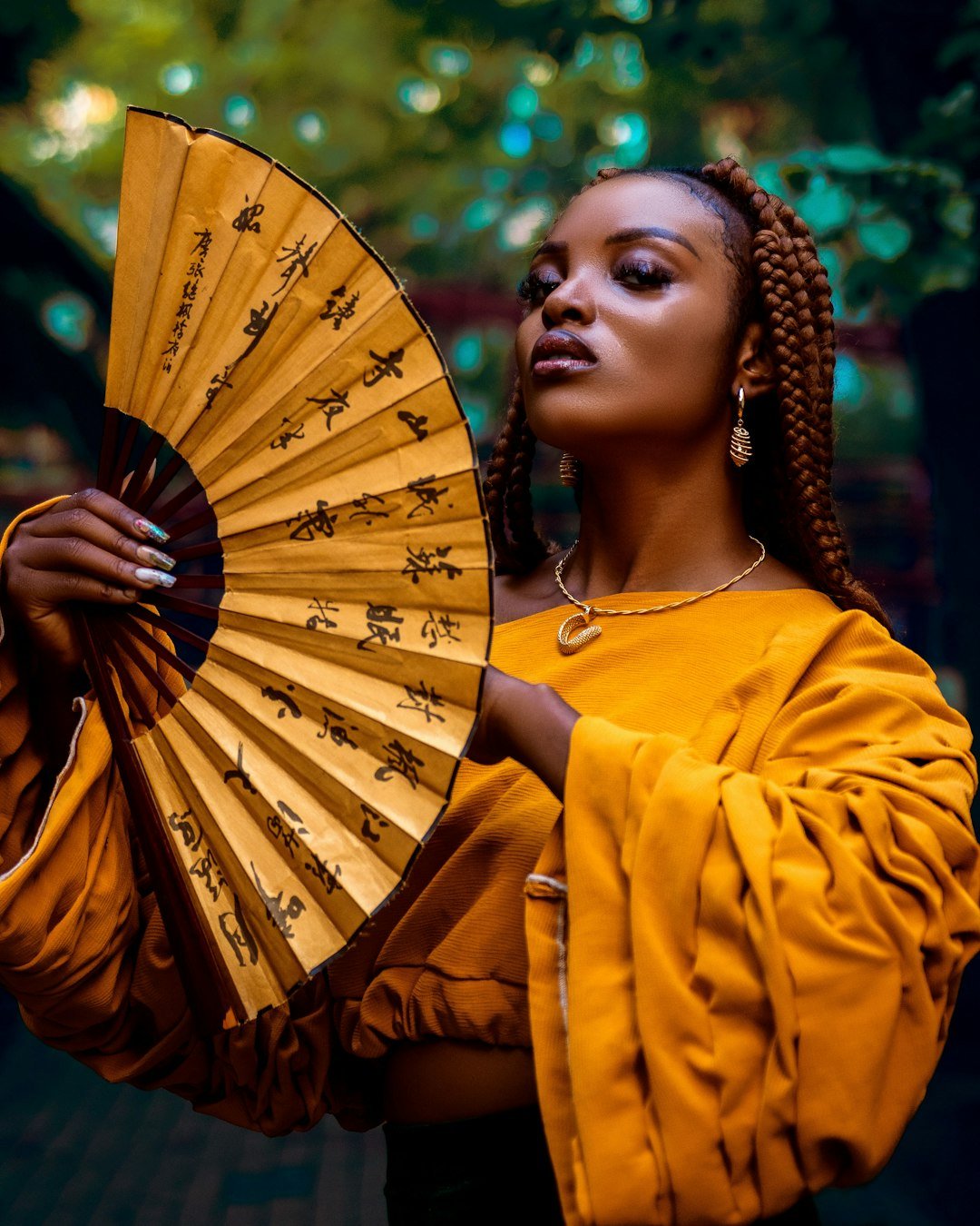 about-us-02 a-woman-with-braids-holding-a-yellow-fan-kjuc35qbbtm